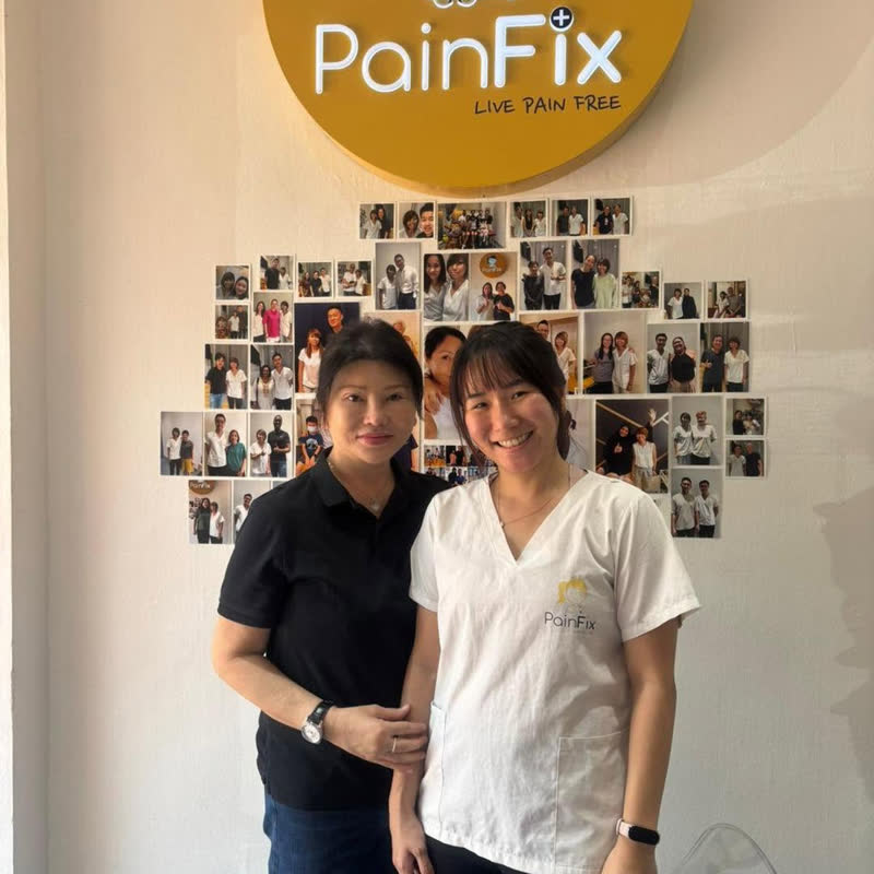 A patient at Painfix Clinic in front of the patient photo wall